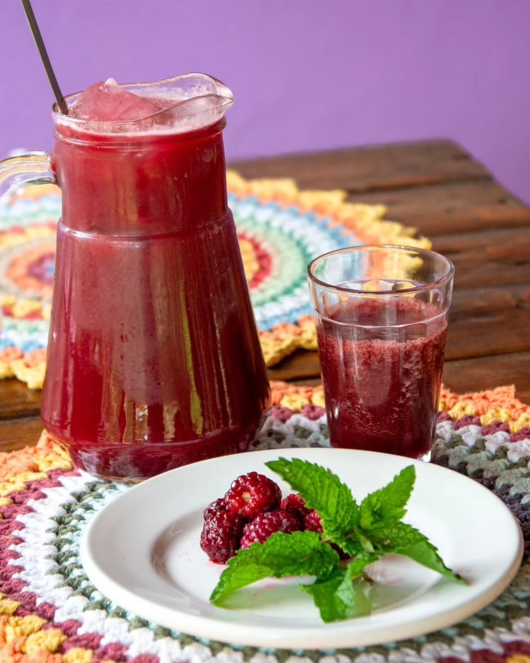 Jarra e copo de bebida de frutas vermelhas servida no Quintal da Cau